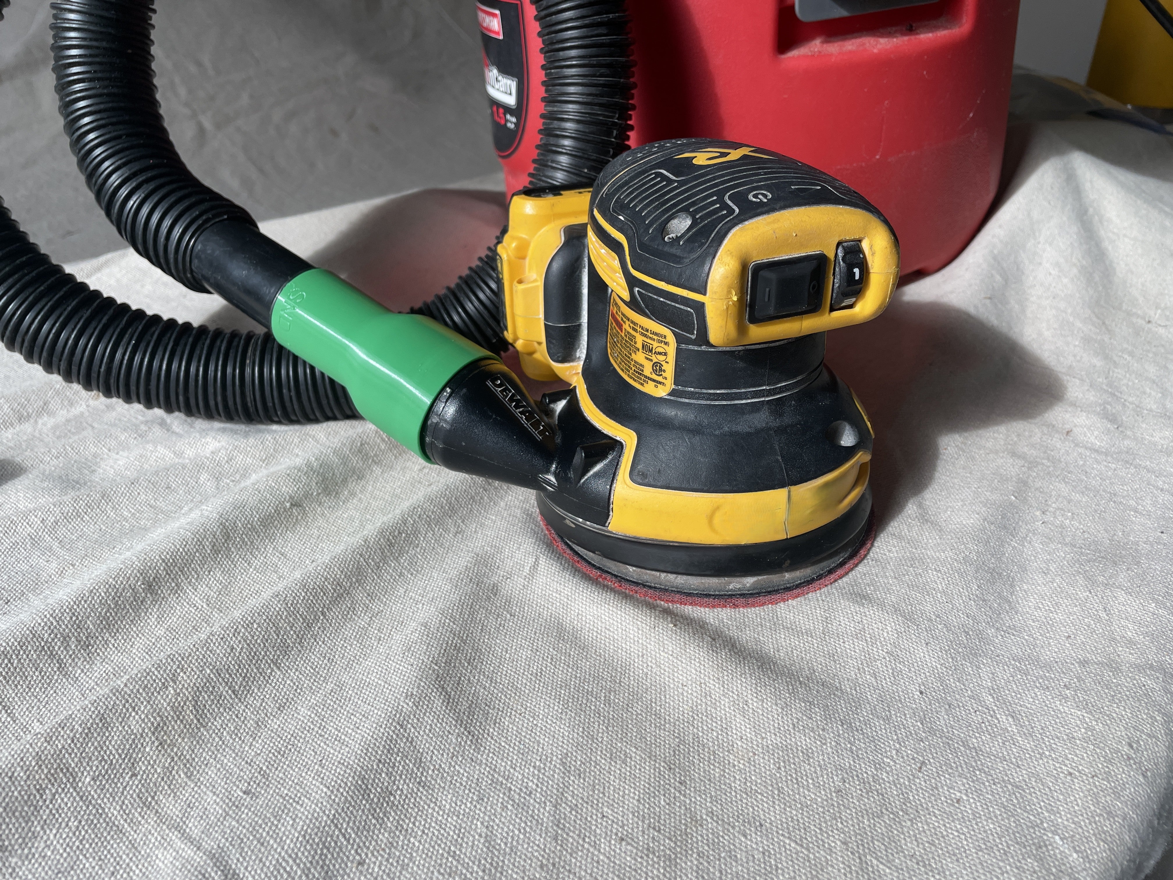 Vacuum adapter connecting a cordless sander to a vacuum hose